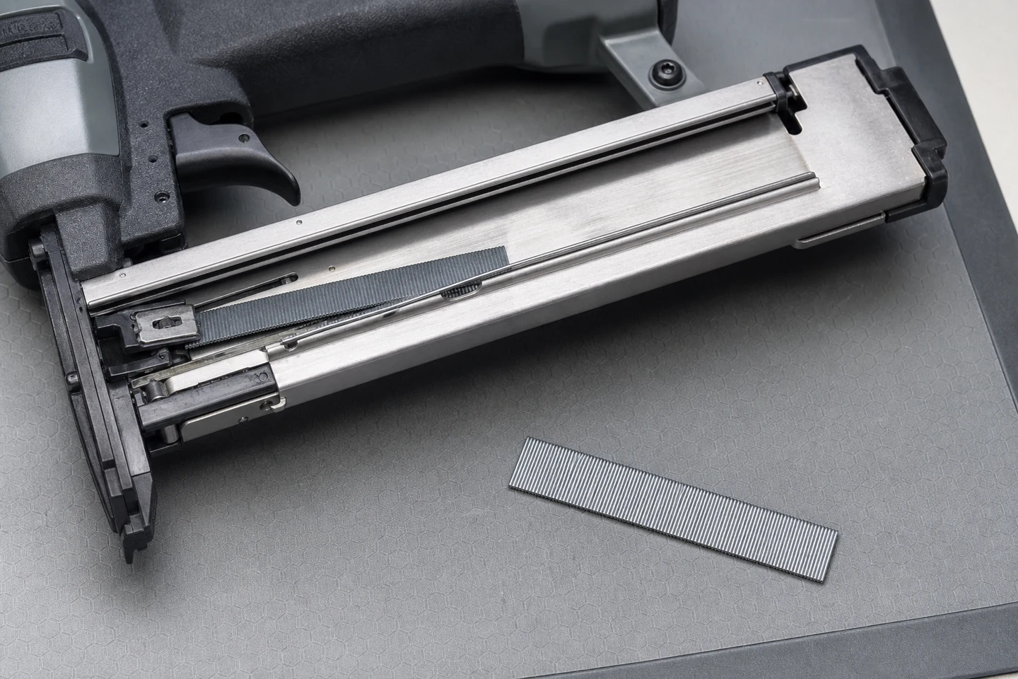 Open pin nailer magazine showing a skewed strip in the steel feed rail beside a control strip