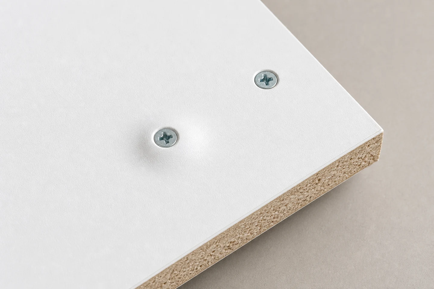 White laminated chipboard with a smooth raised bulge around one screw head beside a correctly seated control screw